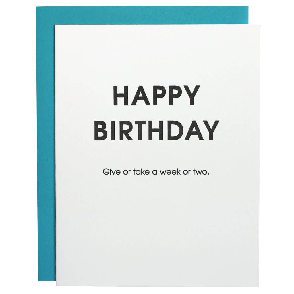 White card with " Happy birthday give or take a week or two" in black lettering.  Fluorescent blue envelope.