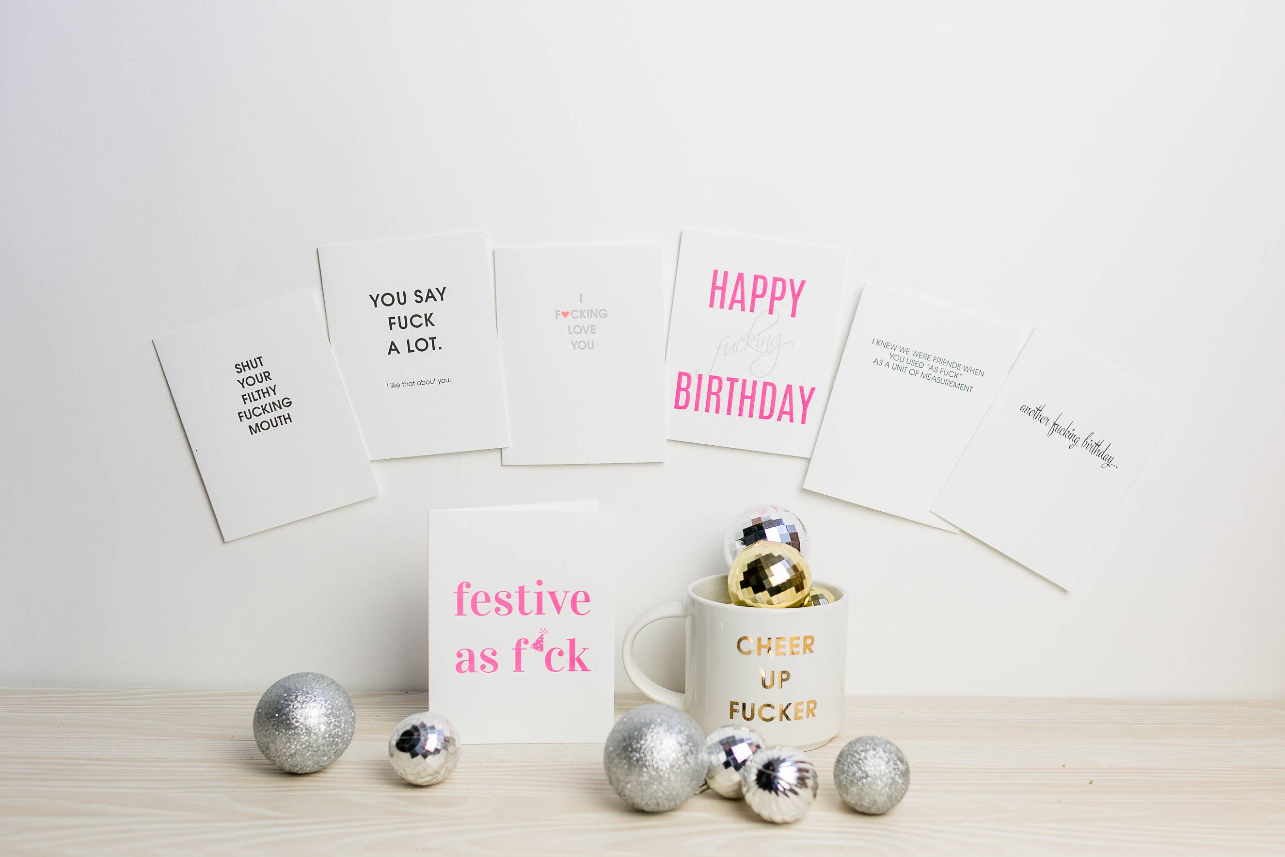 White greeting cards on wall, with various phrases in black or pink text.