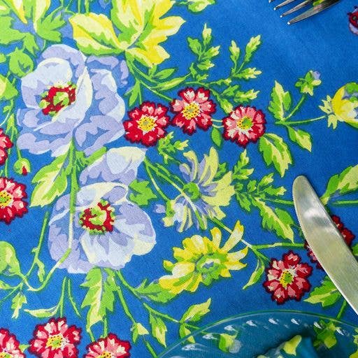 Blue cotton tablecloth with red, yellow and white flowers, and green foliage.