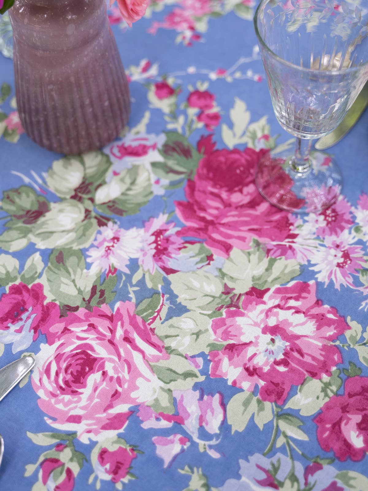 Cotton tablecloth with blue background bright pink floral pattern with green foliage. 