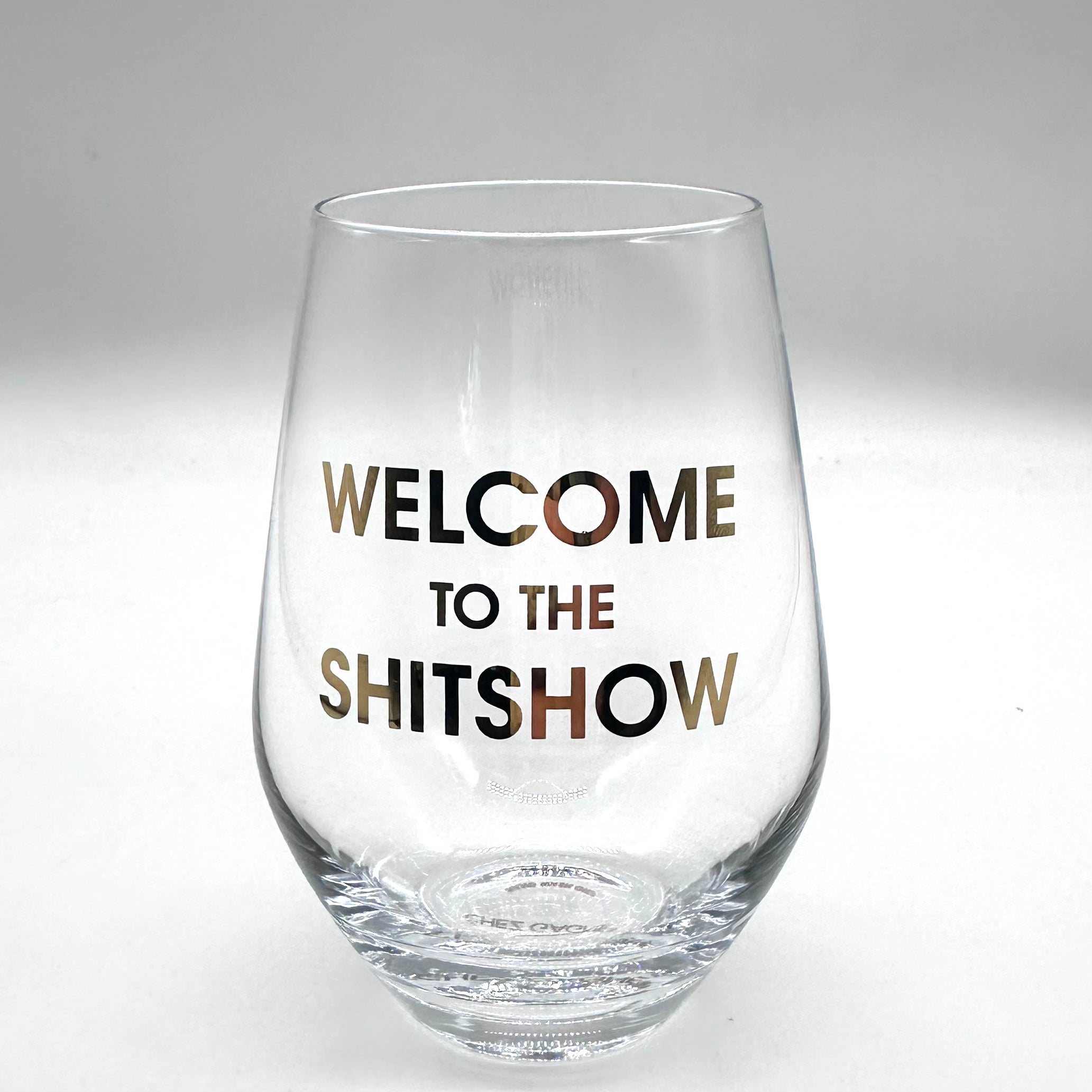 Clear wine glass "WELCOME TO THE SHITSHOW" in gold lettering.