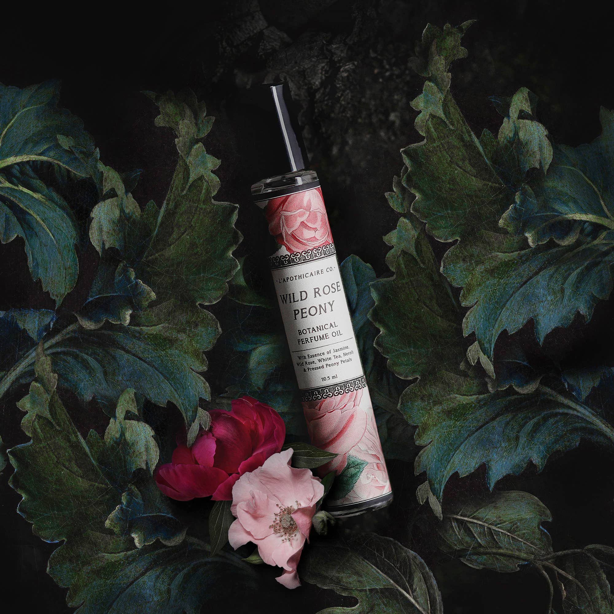 Glass perfume tube, with black lid.  Illustrations of pink roses and peonies on label with black text stating "Wild Rose and Peony botanical perfume oil"