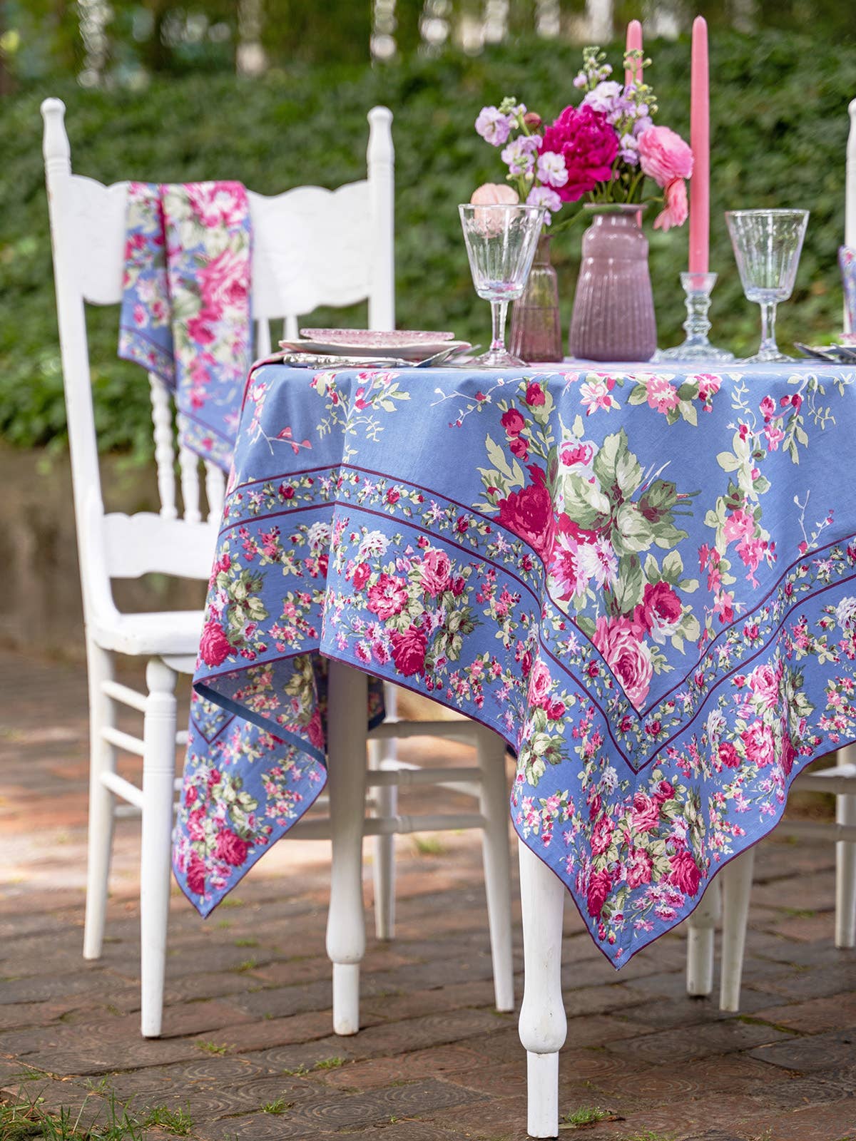 Cotton tablecloth with blue background bright pink floral pattern with green foliage. 