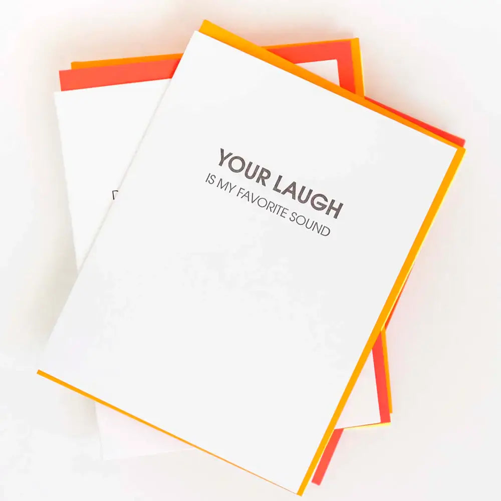 White card with "your laugh is my favorite sound" in black lettering.  Neon orange envelope.