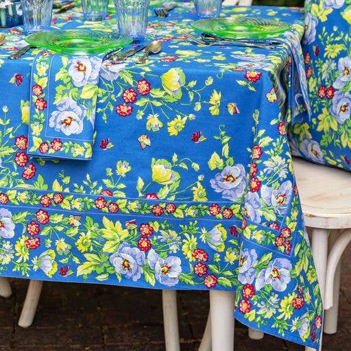 Blue cotton tablecloth with red, yellow and white flowers, and green foliage.