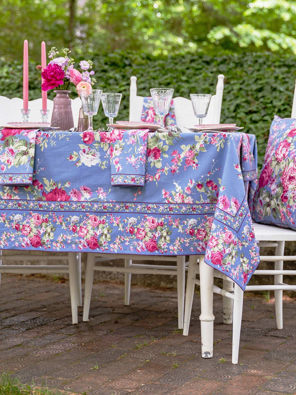 Cotton tablecloth with blue background bright pink floral pattern with green foliage. 