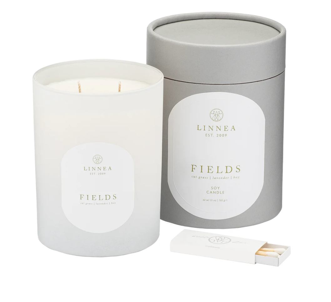 Candle is in a frosted white glass container with white soy wax, it has two wicks. The packaging for the candle is pictures and is a grey carboard cylinder with a lid. The packaging has a set of matches inside of the lid in each product. 