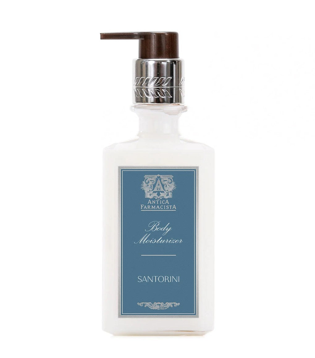 Image of moisturizer in clear plastic bottle with black pump lid, moisturizer is white in color. Blue label with white writing stating "Body Moisturizer Santorini"